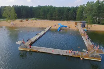 a pier in a body of water with a beach at Erdvus butas su balkonu šalia ežero ir stadiono in Visaginas