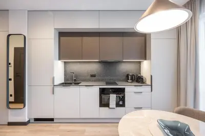 a kitchen with white cabinets and a table at Brand New Downtown Apartments by Reside Baltic in Vilnius