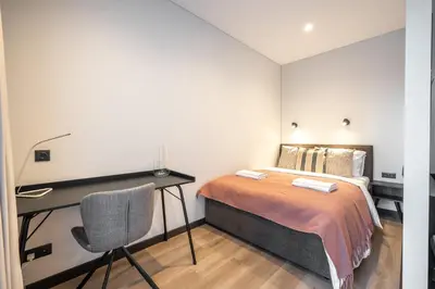 a bedroom with a bed and a desk and a chair at Brand New Downtown Apartments by Reside Baltic in Vilnius