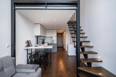 a living room and kitchen with a staircase in a house at Modern Loft Walk to Center Fast Wi-Fi in Vilnius