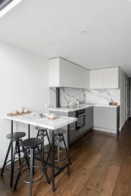 a kitchen with white cabinets and a table and stools at Modern Loft Walk to Center Fast Wi-Fi in Vilnius