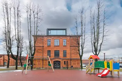 a playground in front of a building with a tower at Shanti barracks apartment by Polo Apartments in Kaunas