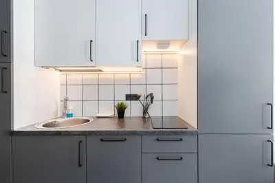 a kitchen with white cabinets and a sink at River To The City - Self check in in Vilnius