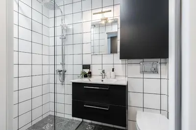 a white tiled bathroom with a sink and a shower at River To The City - Self check in in Vilnius