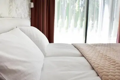 a white bed in a room with a window at Parko Aveniu Apartamentai B4 in Birštonas