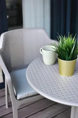 two plants sitting on a table with a chair at Parko Aveniu Apartamentai B4 in Birštonas