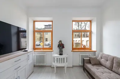 a living room with a couch and two windows at Sophisticated Old town apartment by Polo Apartments in Kaunas