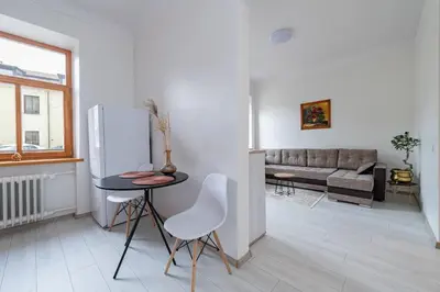 a white living room with a table and a refrigerator at Sophisticated Old town apartment by Polo Apartments in Kaunas