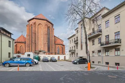 a large brick church with cars parked in a parking lot at Sophisticated Old town apartment by Polo Apartments in Kaunas