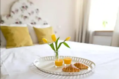 a tray with two cups of orange juice and croissants on a bed at Bright apartment in Old Town by URBAN RENT in Vilnius