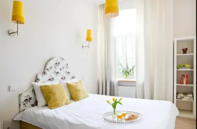 a bedroom with a white bed with a table on it at Bright apartment in Old Town by URBAN RENT in Vilnius
