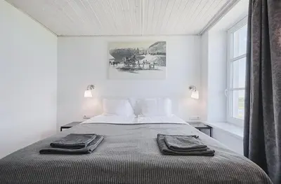 a white bedroom with a bed with two towels on it at Bebryno slėnis in Staškūniškis