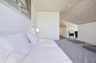 a bedroom with a white bed with a wooden ceiling at Bebryno slėnis in Staškūniškis