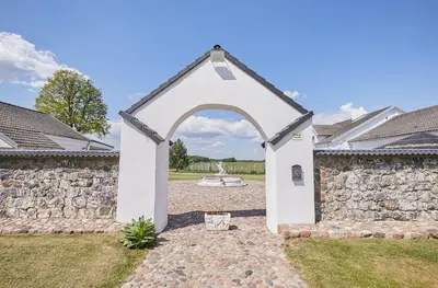 an archway in a yard with a stone wall at Bebryno slėnis in Staškūniškis
