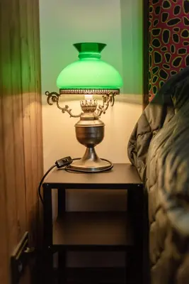 a green lamp on a table next to a bed at Aušrinės in Liškiava
