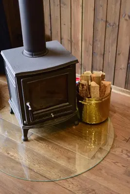 a wood stove with a basket of logs on the floor at Aušrinės in Liškiava