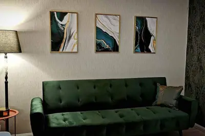 a green couch in a living room with four paintings at Apartaments in Šiauliai center in Šiauliai