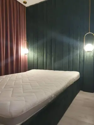 a bed in a room with a green wall and two lights at Apartaments in Šiauliai center in Šiauliai