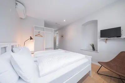 a white bedroom with a bed and a tv at Lollo Luxury Residence - Lollo Stay in Vilnius