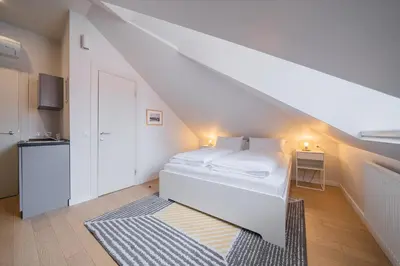 a white bedroom with a bed and a staircase at Lollo Luxury Residence - Lollo Stay in Vilnius