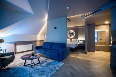 a living room with a blue couch and a bed at CONTI HOTEL VILNIUS, Conference Centre, Restaurant & Bar in Vilnius