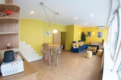a living room with yellow walls and a table and chairs at Laisves alley 50 in Kaunas