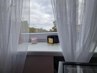 a window with a white curtain and a candle at MilaAna in Visaginas