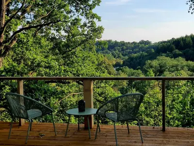 two chairs and a table on a deck with trees at 