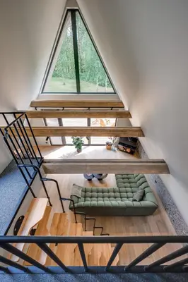 a loft with a window and a couch in a room at Namas MIŠKE in Lazdinė