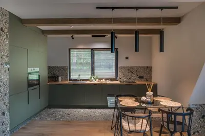 a kitchen with a table and chairs and a counter at Namas MIŠKE in Lazdinė