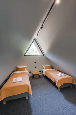 two beds in a attic bedroom with a window at Namas MIŠKE in Lazdinė