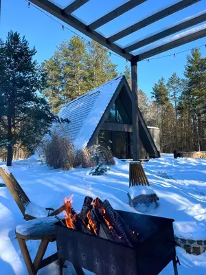 a fire pit in front of a house in the snow at Namas MIŠKE in Lazdinė