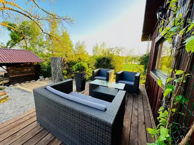 a patio with wicker furniture on a wooden deck at AGUONA ROYAL OASIS in Molėtai