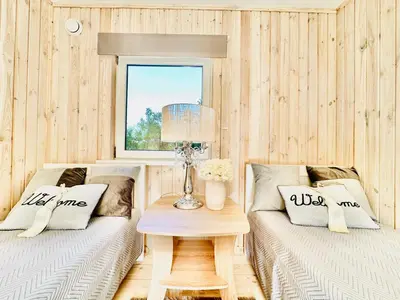 two beds in a room with a table and a window at AGUONA ROYAL OASIS in Molėtai