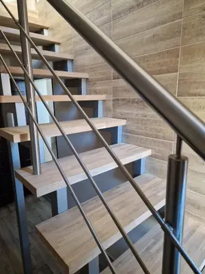 a wooden staircase with a metal handrail and wooden floors at Alvydo apartamentai in Kaunas