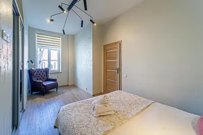 a bedroom with a bed and a blue chair at Kaunas Heart Apartment in Kaunas