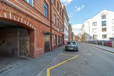 a car parked on a street next to a brick building at Kaunas Heart Apartment in Kaunas