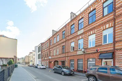 a street with cars parked in front of a brick building at Kaunas Heart Apartment in Kaunas