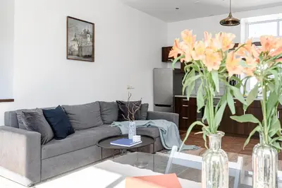 a living room with a gray couch and vases with flowers at Spacious City Centre Apartment with Parking SELF CHECK-IN in Vilnius