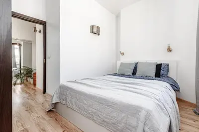 a white bedroom with a large bed with blue pillows at Spacious City Centre Apartment with Parking SELF CHECK-IN in Vilnius