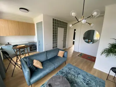 a living room with a blue couch and a kitchen at Šiauliai CENTER Višinskio NEW self check In in Šiauliai