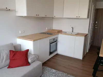 a small kitchen with white cabinets and a couch at Stylish Studio in Central Vilnius II in Vilnius