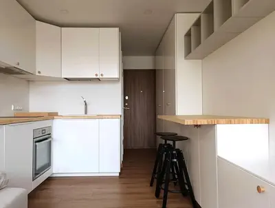 a kitchen with white cabinets and bar stools in it at Stylish Studio in Central Vilnius II in Vilnius