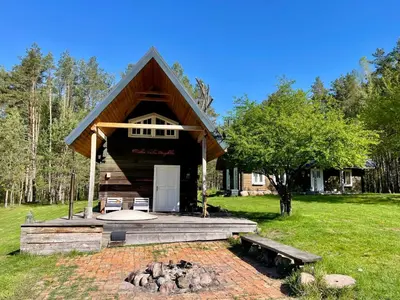 a log cabin with a porch and a fire pit at Holiday homestead Camp of Forest Souls in Masališkės
