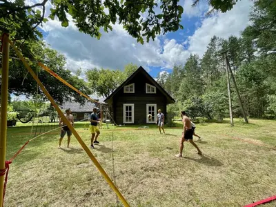 a group of people playing a game in front of a house at Holiday homestead Camp of Forest Souls in Masališkės