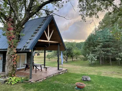 a small cabin with a wooden deck and a picnic table at Holiday homestead Camp of Forest Souls in Masališkės