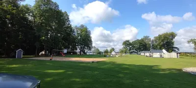 a large green field with trees and a playground at Perlytė in Metelyte