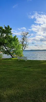 a park bench sitting in the grass near the water at Perlytė in Metelyte