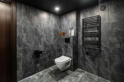 a bathroom with a toilet and a tiled wall at Radio City loft - apartment 420 in Kaunas
