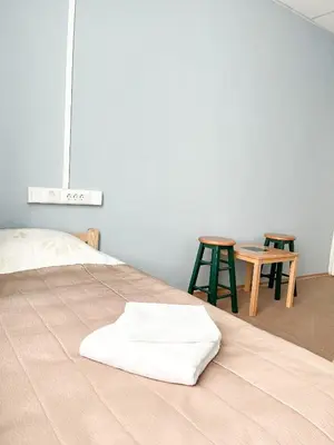 a bed with a white blanket on it with two tables at Apgyvendinimo įstaiga KORNEALITA in Zarasai
